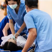 Medical team do CPR Cardiopulmonary resuscitation to seriously injured patient with oxygen mask while push gurney stretcher bed to Operating Room. Emergency health care and medical hospital concept.