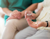 Nurse consoling her elderly patient by holding her hands