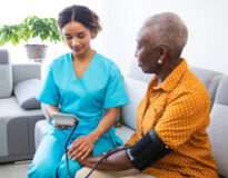 nurse visiting a senior patient at home, measuring her blood pressure