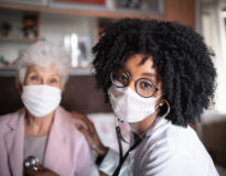 Portrait of health visitor and a senior woman during home visit