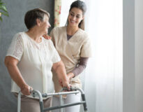 Smiling nurse helping senior lady to walk around the nursing home